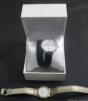 Two wristwatches shown: boxed Mary Kay watch and gold-tone watch below