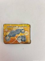 Front of orange box showing image of loupe and wording JEWELER’S LOUPE