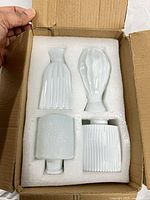 Four blue ceramic bud vases inside foam packaging