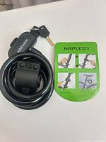 Front view of coiled Hapleby cable lock with mount, key inserted, and instruction card