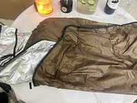 Brown poncho laid flat showing exterior shell and interior silver lining