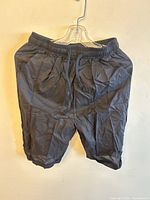 Front view of black synthetic athletic shorts on hanger