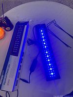 LED fixture illuminated blue alongside box, power cord visible