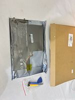 Battery in anti-static bag beside screwdrivers and pry pick