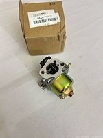 Carburetor in front of original plain box showing barcode label