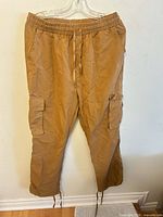 Full view of tan cargo jogger pants front showing pockets, waistband, cuffs
