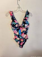 Full view of floral one-piece swimsuit hanging on clear hanger