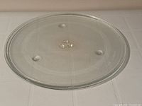 Top view of clear 15 in glass microwave tray showing support bumps and hub fitting