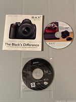 Three software CDs displayed on flat surface: Black's Difference sleeve top left, Black's Digital Solutions disc top right, Nikon Software Suite disc bottom