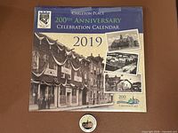 Front view of sealed 2019 Carleton Place 200th Anniversary Celebration Calendar with button pin in foreground