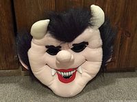 front view of stuffed monster mask showing face, horns, hair and fangs
