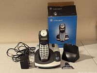 Complete GE cordless phone set showing handset, base, power adapter, belt clip, handset holder and retail box