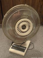 Front view of beige oscillating table fan showing grille and control panel