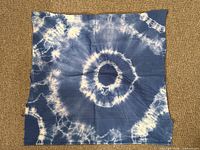 Full view of square blue and white tie-dye cotton cloth laid flat