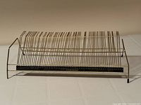 Front angled view of brass-tone wire record rack showing 60 slots and numbered indicator bar