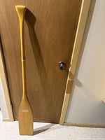 Full view of the wooden canoe paddle leaning against door