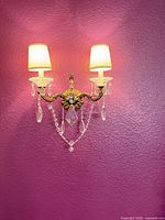 Single brass and crystal 2-arm sconce on wall with silk shades
