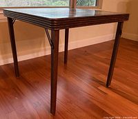 Full view of antique folding card table showing wood frame and legs