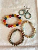 Group shot of three beaded bracelets and green hoop earrings