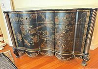 Front view of black chest showing floral and bird stencil artwork and serpentine drawers