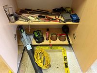 Cabinet with blower, battery, charger, extension cord, flashlight, plunger, gloves, assorted tools