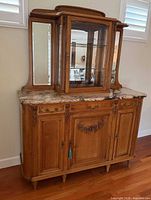 Full frontal view of buffet and glass hutch showing marble top, carved doors, glass cabinet