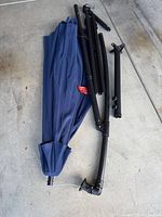 Disassembled blue canopy and black pole sections on concrete