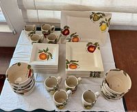 Full set displayed on table showing plates, bowls, mugs, platter