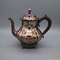 front view of teapot showing overall form, patina, decorative feet