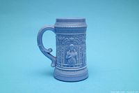 Front view of blue milk glass stein mug showing musician relief