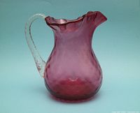 Left profile of cranberry glass pitcher showing hobnail dimples and clear twisted handle