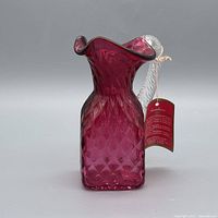 Front view of cranberry glass pitcher showing diamond optic pattern and flared rim