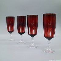 Four ruby red cut-to-clear champagne flutes aligned