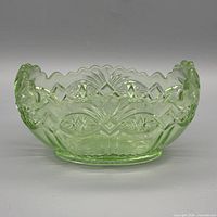 Front view of green pressed glass bowl showing geometric pattern and scalloped rim