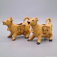Two yellow/tan glazed ceramic cow creamers with California decal, side view