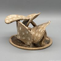 Front view of speckled stoneware mushroom sculpture showing clustered caps and round base.