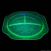 Plate glowing bright green under UV light showing uranium content and divider