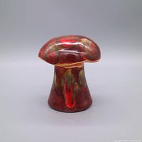 Front view of red glazed mushroom shaker showing cap and stem coloration