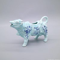 Left side view of cow creamer showing pale aqua glaze and blue Cape Cod Mass transfer decoration