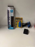 Boxed Belkin surge protector, Painter's Pyramid package, hose nozzle, sanding block