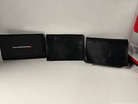 Three document wallets side by side: Dodge logo on left, two Cadillac crest on right