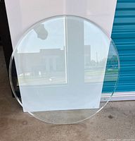 Full view of clear round glass tabletop leaning against wall