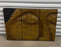 Front view of three-panel carved wood Buddha face art