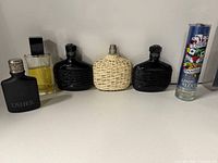 Front view showing six perfume bottles: Usher, clear rectangular, two black ridged, tan wicker, Ed Hardy cylinder