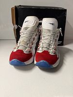 Front view of both sneakers with box behind