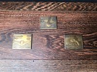 Front view of three bronze Olympic stamp replicas