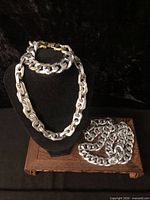 Necklace and bracelet on bust, additional chain on wooden stand