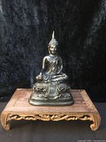 full view of Buddha statue on wooden stand