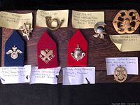 Eight Dutch Army badges laid out with handwritten annotations