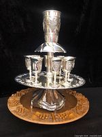 Kiddush wine fountain assembled on carved oak tray showing central goblet, stand, eight cups and tray